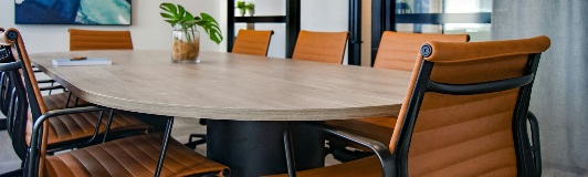 wood meeting table with orange chairs around it