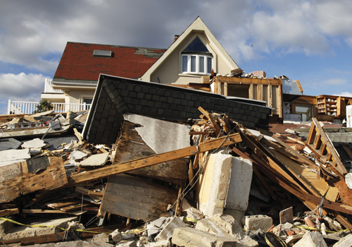 hurricane damage pile of rubble in front of home with red roof