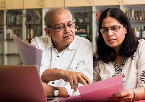 elderly couple discussing information on printed documents