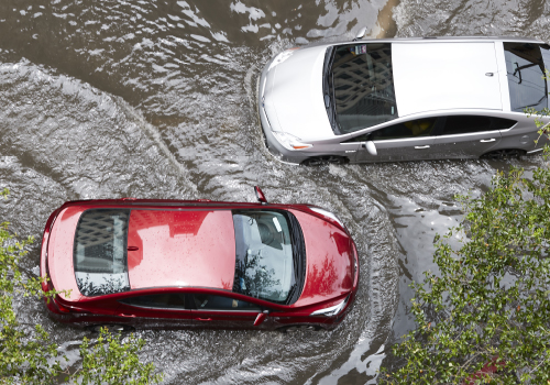 two sedan vehicles driving through a flooded street