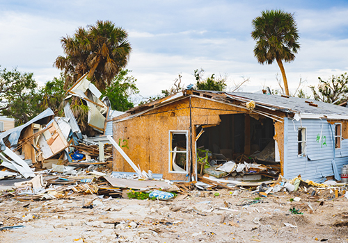 severely damage single story home surrounded by debris