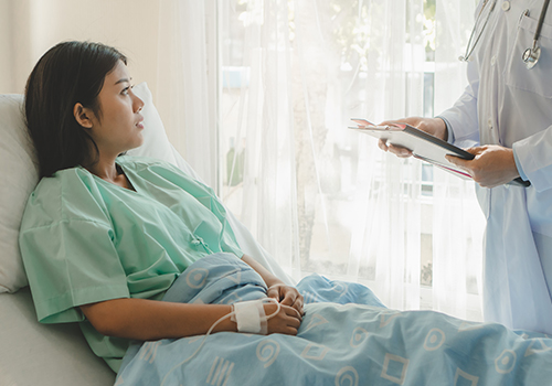 patient in hospital bed speaking with physician