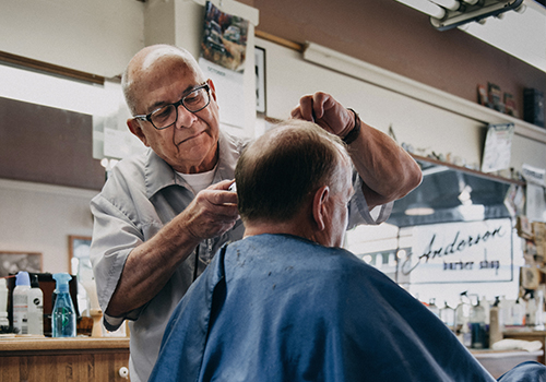 senior barber trimming the hair of a client in a chair