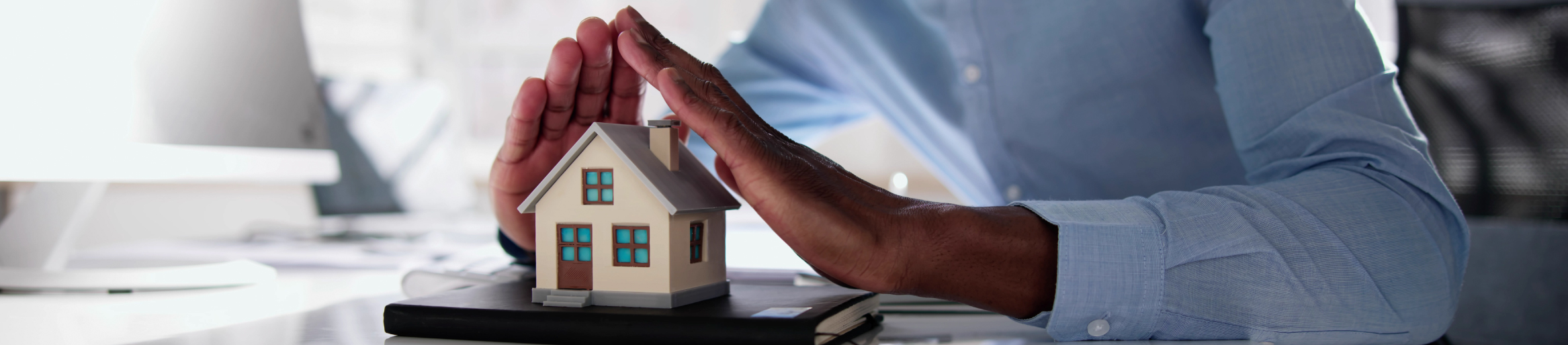 Coverage Banner Man using hands to protect small model of a home, demonstrating "coverage"