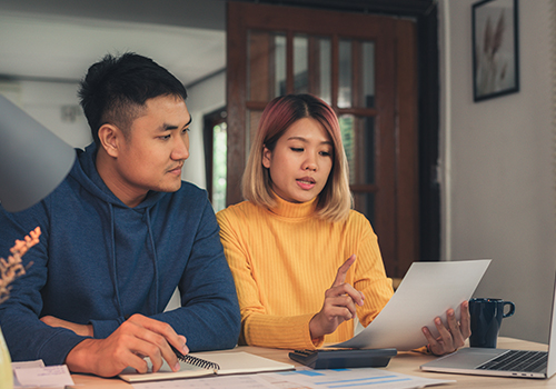 Una pareja de jóvenes asiáticos sentados hablando sobre finanzas