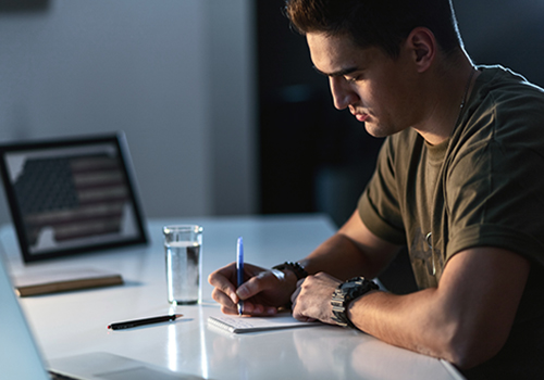 budget-sheet_thumb military servicemember writing in notebook on desk