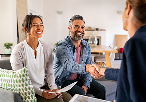 Latin couple smiling and shaking hands with business woman